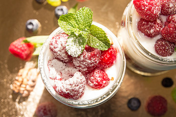 Healthy breakfast - dessert with yogurt, granola, outs flakes, jam, raspberries, blueberries, hazelnut and mint
