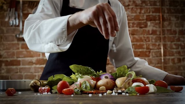 Cookery lessons. A cook sprinkling with salt products prepared for cooking a meal. 4K