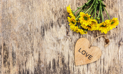 Naklejka premium Summer yellow flowers and heart on a wooden background. Copy space