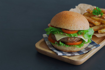 Homemade hamburger on plaid napkin with french fries. Delicious sandwich hamburger with meat or pork ham cheese and fresh vegetable. Hamburger or sandwich is the popular fast food for brunch or lunch.