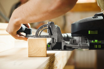 Man working with carving equipment in workshop. Electronic device