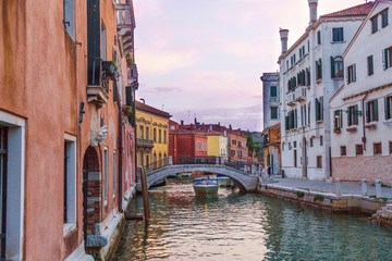 Venetian cityscape at sunset time: bridges, typical Venetian buildings and amazing sky.
