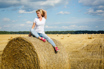 Naklejka na ściany i meble Girl sitting on the hay bale, Tubala windmill in the background,