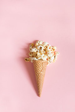 Popcorn in ice cream cones on pink background. Top view. Vertical.