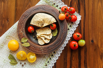 homemade cheese,tomatos with herb spice in rural pottery.table napkin.wooden background