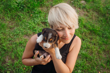 Blonde woman plays with a puppy on green lawn
