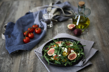 Fresh salad with arugula tomato and cheese on wooden background