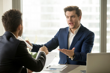 Businessmen arguing at workplace, disagreeing over document, partners having conflict while...