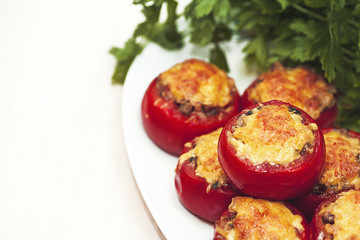 Stuffed mushrooms tomatoes with cheese baked in the oven on a background of green parsley. Vegetarian dish.
