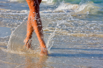  woman's legs go along the sand near the sea.