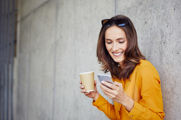 Portrait of attractive young woman using phone and drinking coffee