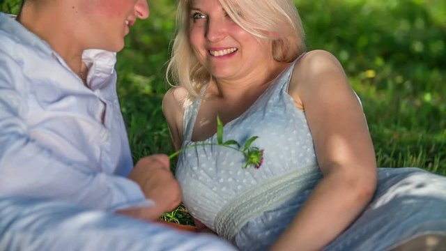 A young man is touching the woman's breasts and neck with a flower. She is biting her lips.