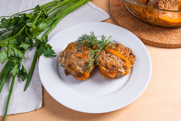 Rissole of pork served on a white plate and herbs - dill, green onion, parsley around the plate.