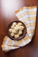 Boiled Ukrainian meat dumplings or ravioli on wooden background.