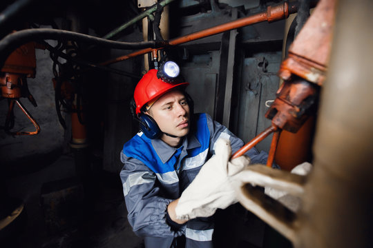 young coal miner is underground in a mine for coal mining in overalls against the backdrop of mining equipment. concept of repair of industrial equipment.