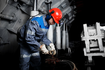 young coal miner is underground in a mine for coal mining in overalls against the backdrop of...