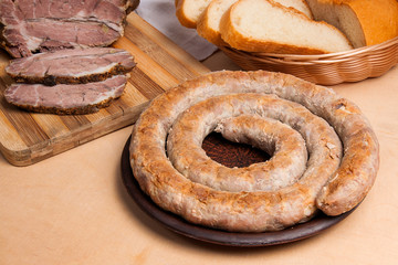 Roasted traditional homemade sausage with spices and herbs. Baked pork with herbs and spice on wooden board and and slices white wheat bread.