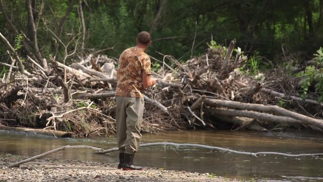 Man fishing on a mountain river with a short ultralight spinning using fishing wobblers