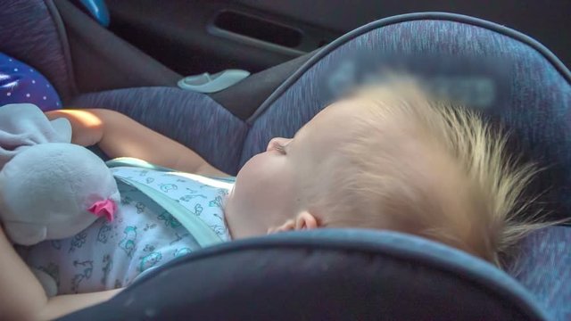 A girl is peacefully sleeping in a child safety seat when a car is driving on a highway somewhere in Slovenia. 