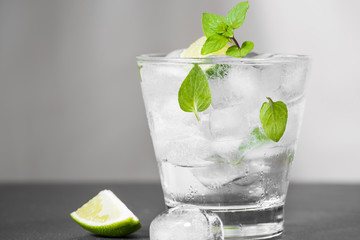 Mojito cocktail with lime and mint in glass on a grey stone background