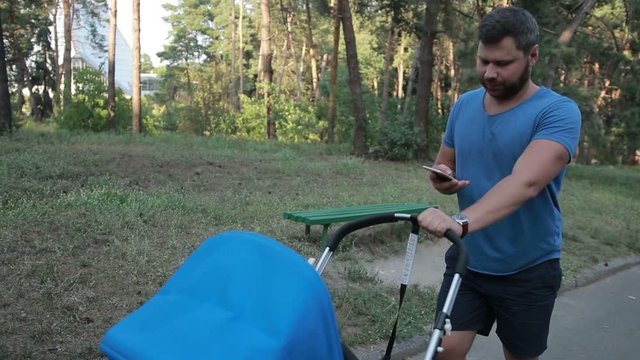 Hipster father with pram walking in public park