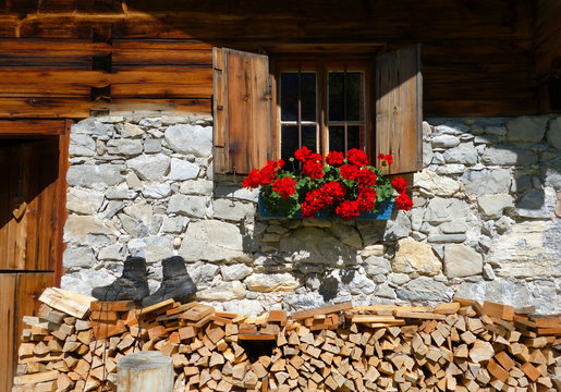 Almh&uuml;tte mit Geranien, Wanderschuhen und Holzstapel