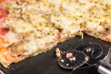 Sliced fresh baked pizza with mushrooms cheese ham ketchup on the round baking pan