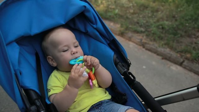 Smiling toddler baby boy sitting in pram outdoors