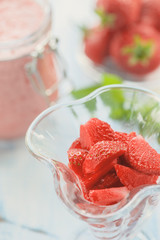 Fruit dessert of strawberries close-up with a dairy cocktail in a glass vase.