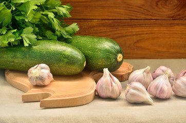 Squashes with parsley among garlic on a wooden background