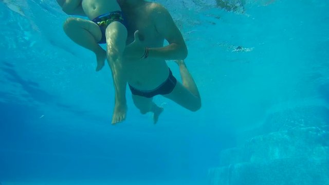 Father and son are dipping under water in the swimming pool