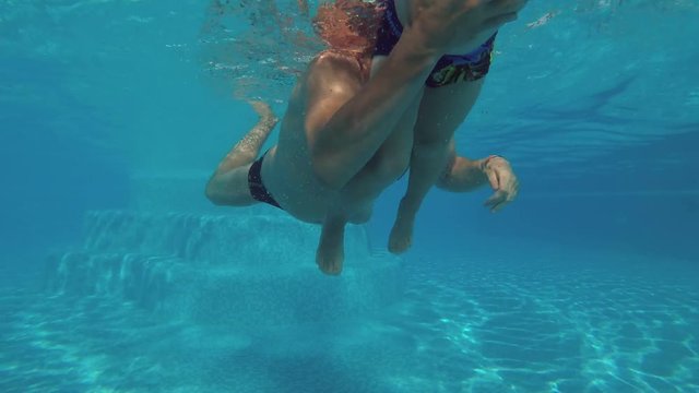 Father and son are dipping under water in the swimming pool