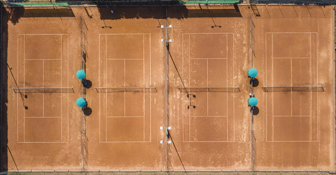 Vista aerea ortogonale di campo da tennis in terra battuta rossa. Ci sono 4 campi ed &egrave; estate perci&ograve; al circolo sportivo non c' &egrave; nessuno.