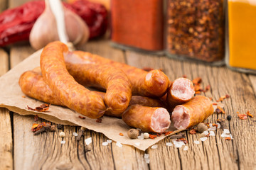 Sausages with spices on an old paper. On old wooden table.