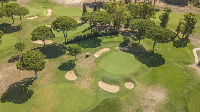 Vista aerea di un campo da golf vuoto con colline verdi e dune di sabbia. Il circolo sportivo è curato e ricco di alberi e vegetazione.