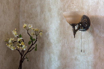 sconce is placed on the wall and the flowers in the corner of the room