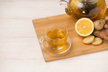 Cup of ginger tea with lemon and honey on white wooden background.