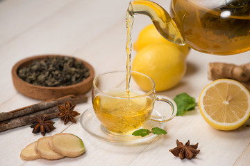 Cup of ginger tea with lemon and honey on white wooden background.