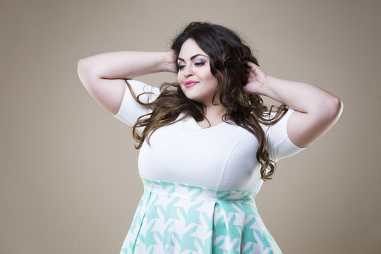 Happy plus size fashion model in casual clothes, fat woman on beige background, overweight female body