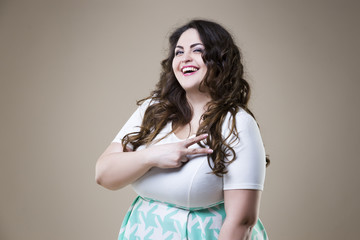 Happy plus size fashion model in casual clothes, fat woman on beige background, overweight female...