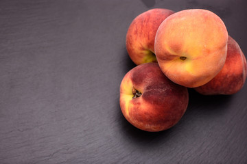 Peaches lie on a black stone slate, place for text