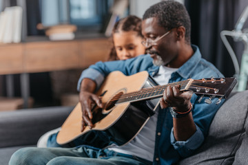 Fototapeta premium man playing guitar with daughter at home
