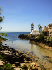 Fototapeta na wymiar Beautiful small beach of Santa Marta in Cascais - transparent water and lighthouse in the background