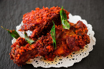 Authentic Indian Chicken fry with spices, curry leaf and coconut - payyoli chicken fry. Famous Kerala course. Copy space. Dark background - obrazy, fototapety, plakaty