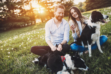 Romantic couple in love walking dogs in nature and smiling
