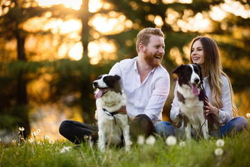 Beautiful couple cuddling and walking dogs outdoors