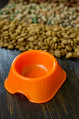 Small orange bowl for pet food and dry food as background.