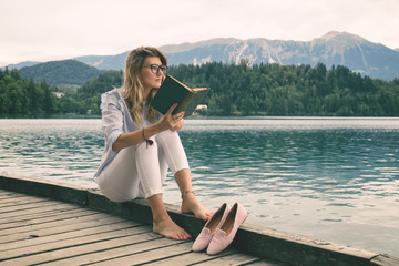 Pretty woman enjoying on the lake and reading a book.