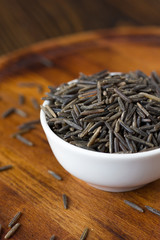 Black wild rice in ceramic bowl over wooden board