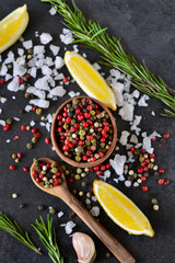 Mix of peppers with salt, rosemary and garlic on shale stone. Black food background with spices. Top view.